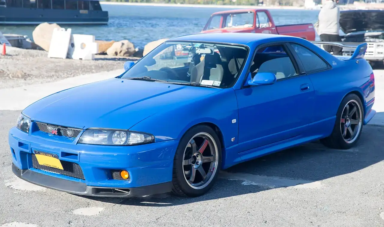 A Japanese performance coupe in metallic blue, front three-quarter view.