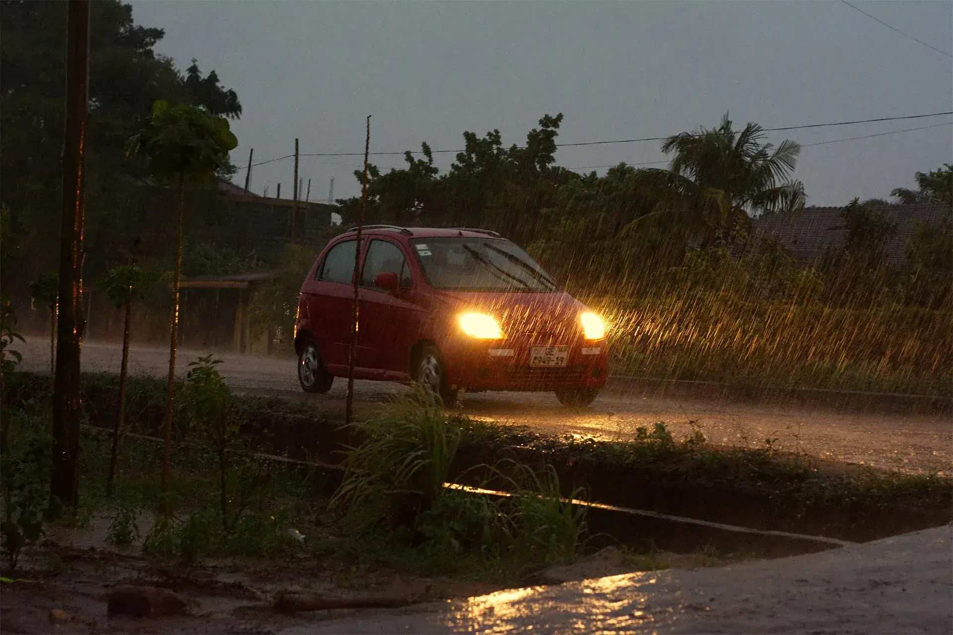 Headlight beams cutting through rain on a dark road.
