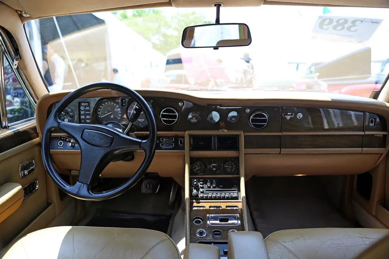 Hand-stitched leather and veneer across the dashboard of a luxury saloon.